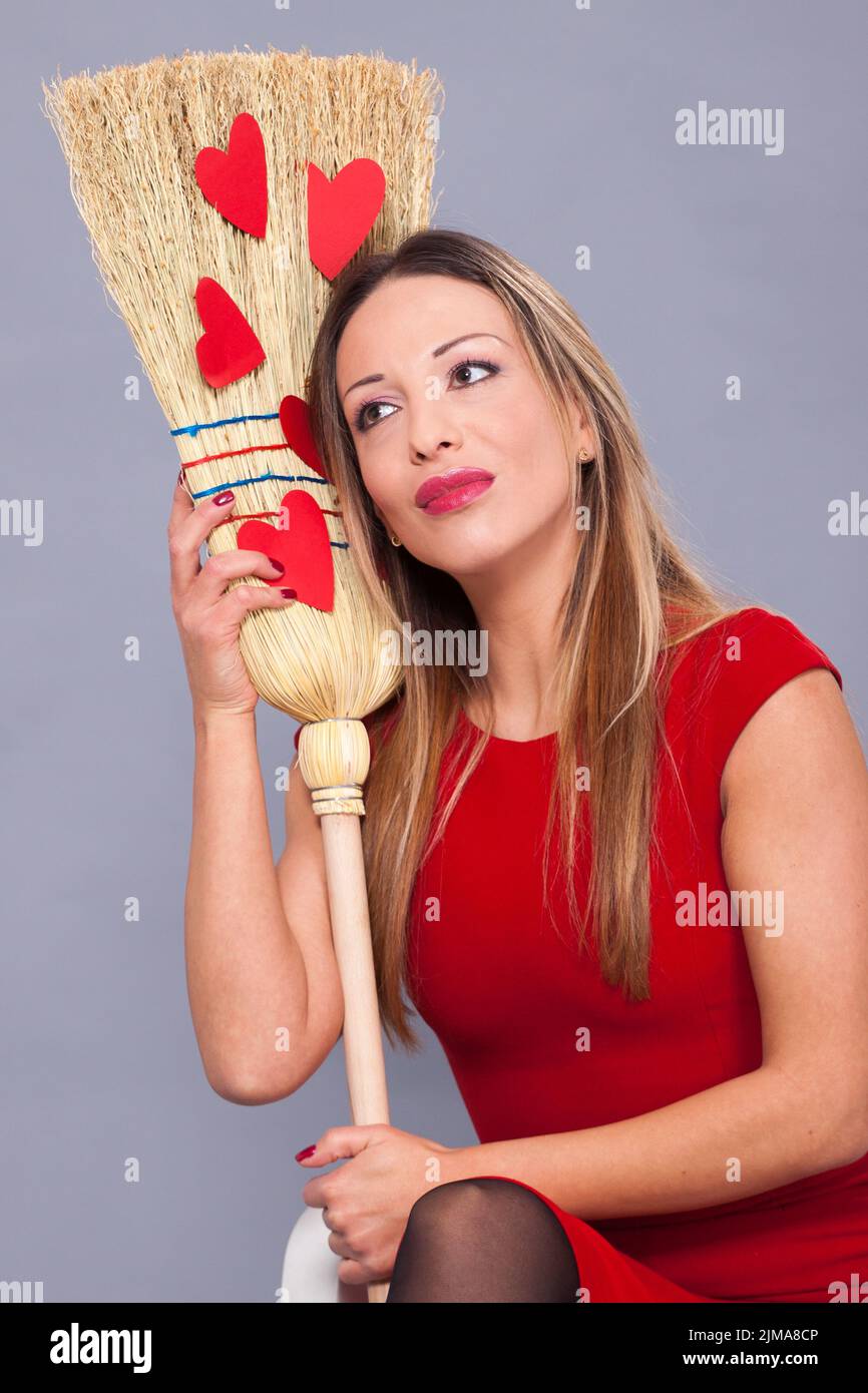 Bella donna che posa con cuori rossi di carta sulla scopa Foto stock - Alamy