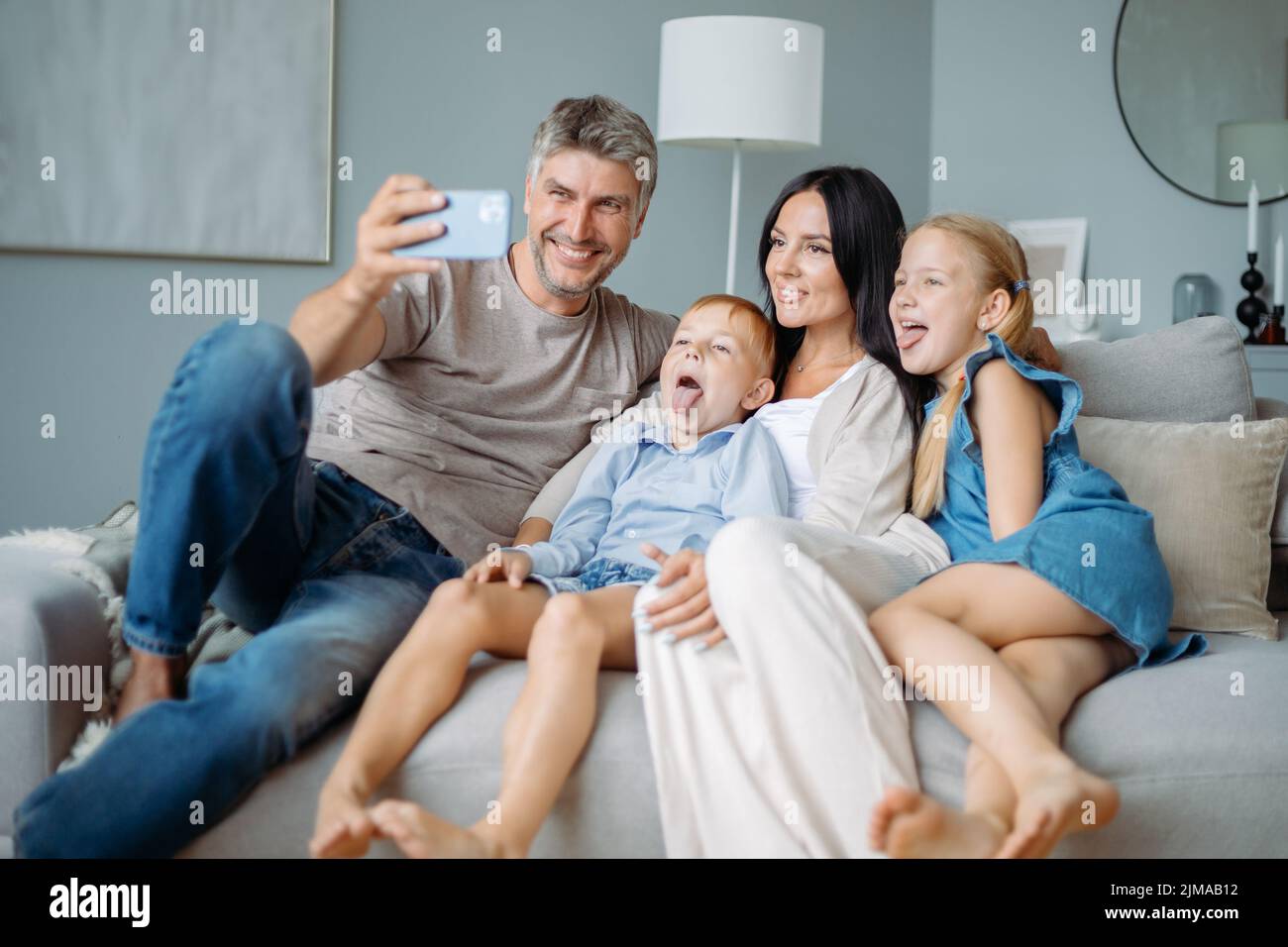 famiglia felice con i bambini che si divertono a scattare selfie seduti sul divano. Foto Stock