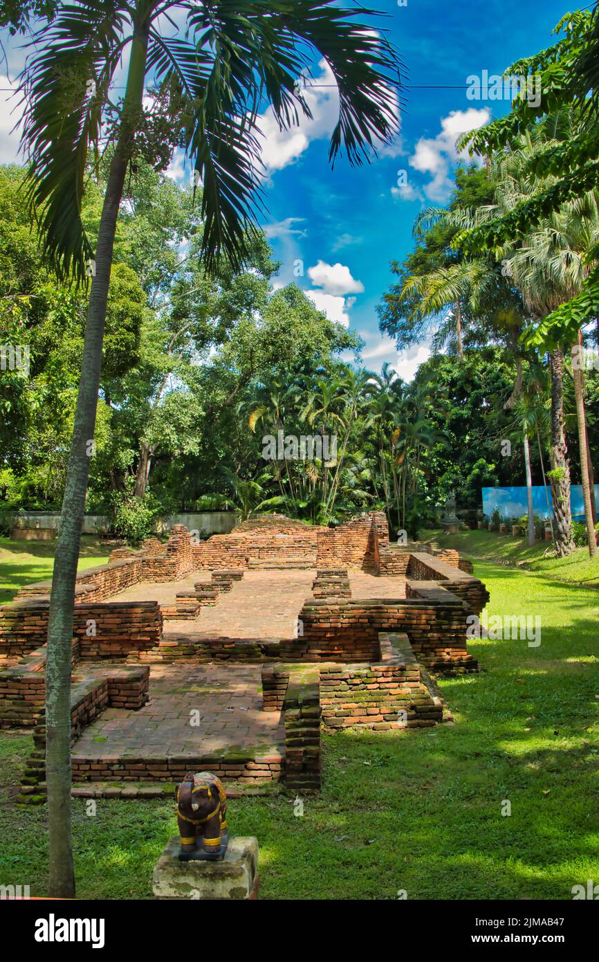 Rovine di tempio di mattoni del Wat Chang Kam, con palme e altra vegetazione tropicale, al sito archeologico di Wiang Kum Kam a Chiang mai, Thailandia Foto Stock
