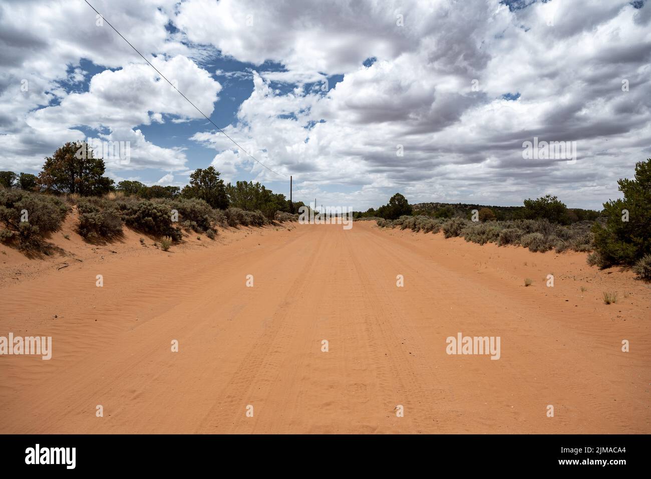 La strada ghiaiosa di sabbia rossa nello Utah conduce sempre dritto. Foto Stock
