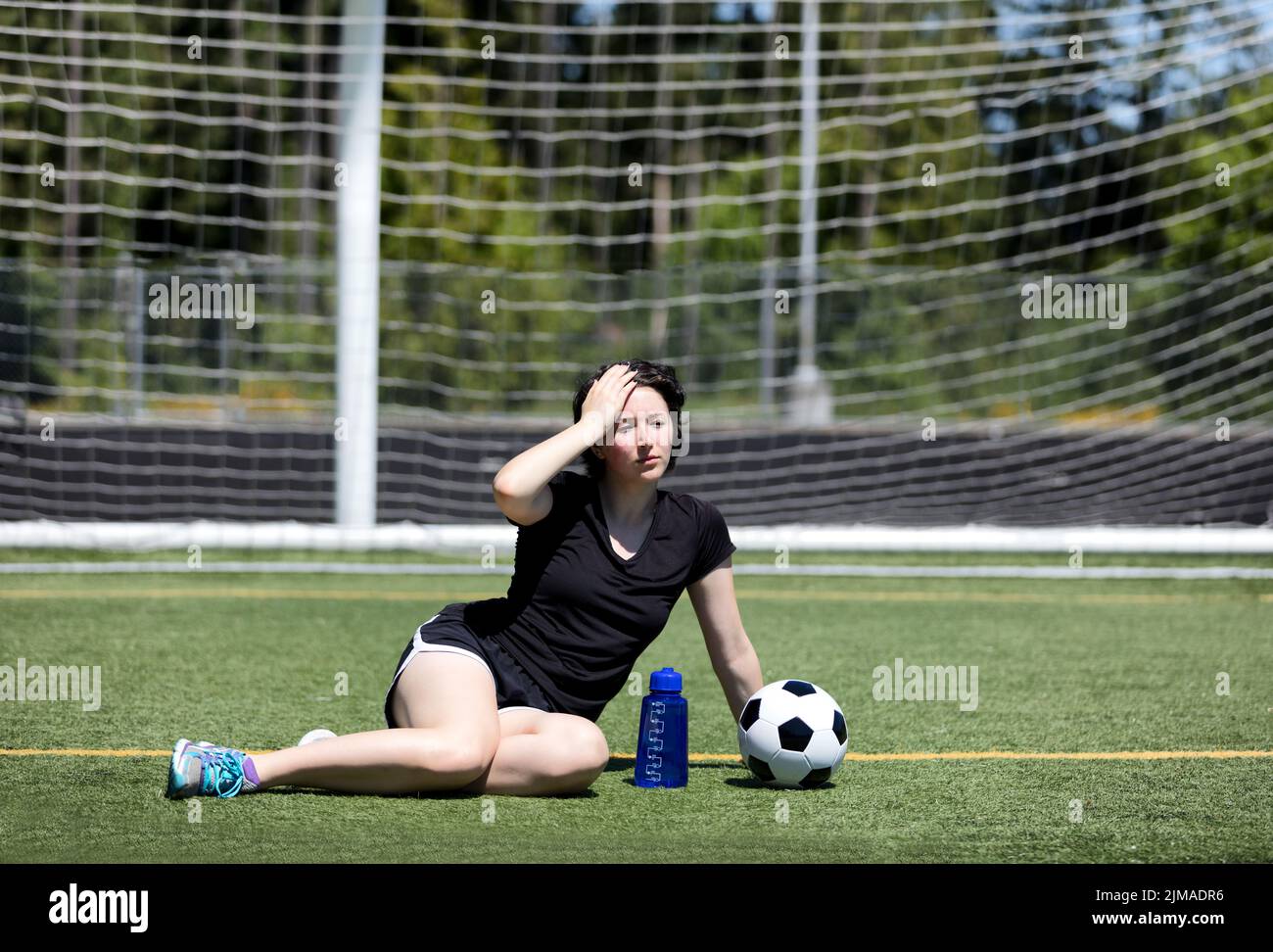 Ragazza teen che si sente troppo caldo sul campo di calcio in giorno caldo Foto Stock
