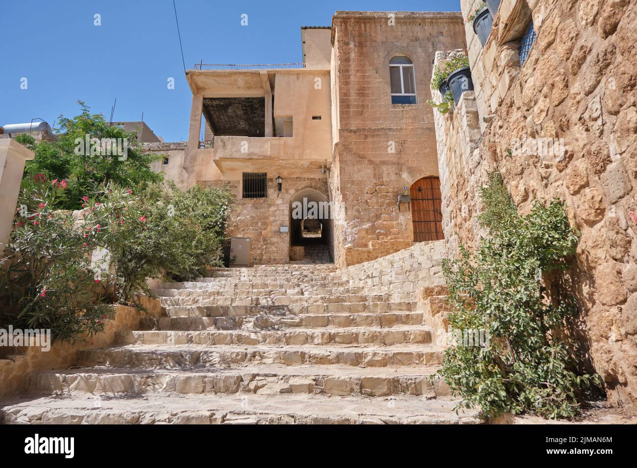 Scale ad angolo basso, scale in pietra calcarea in mardin, antica porta stretta e città coperte da piante verdi. Romantica vita cittadina a Mardin Turchia Foto Stock