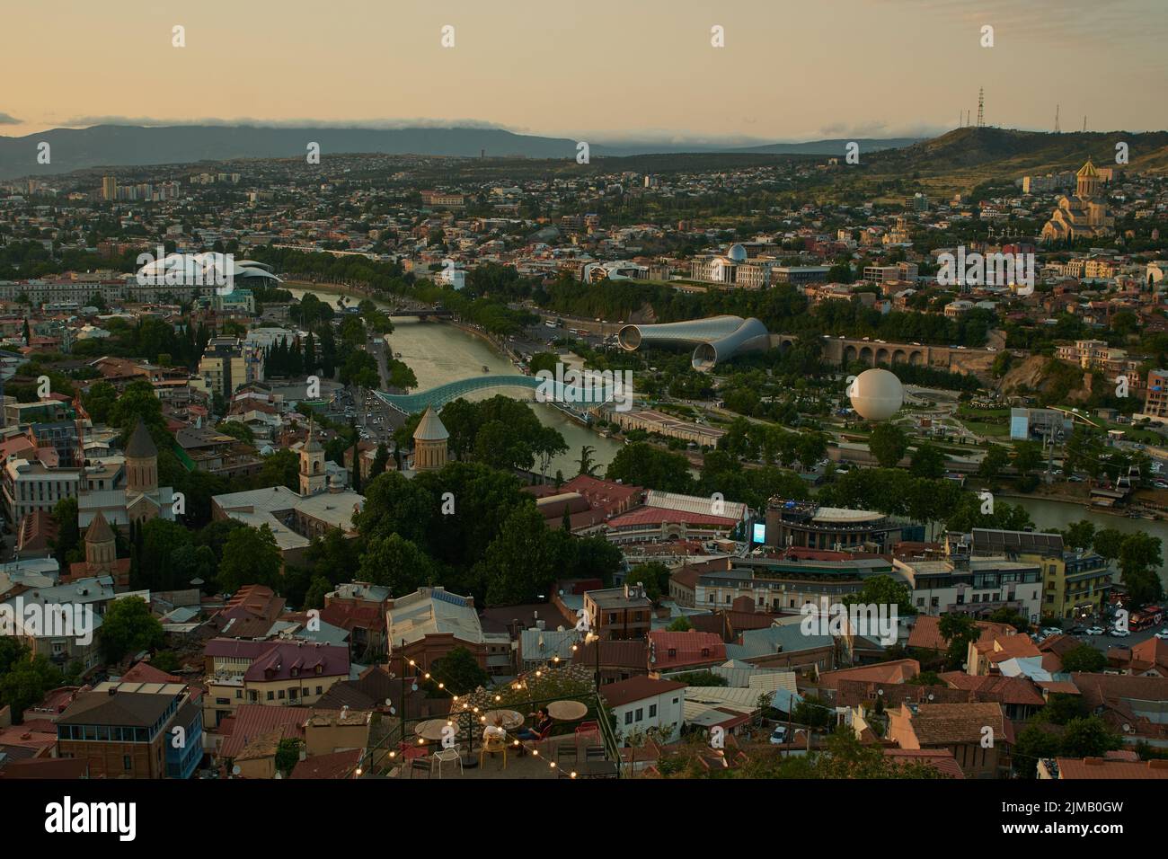 Tbilisi, Georgia tramonto Vista panoramica dalla cima della fortezza di Narikala che mostra il ponte della pace, Rike Park, fiume Kura e Cattedrale della Santissima Trinità Foto Stock