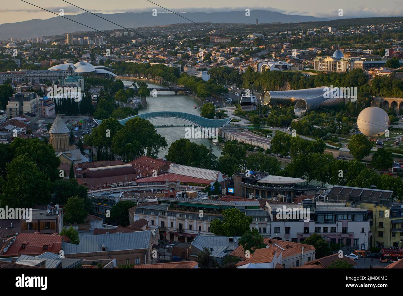 Tbilisi, Georgia tramonto Vista panoramica dalla cima della fortezza di Narikala che mostra il ponte della pace, Rike Park, fiume Kura e Cattedrale della Santissima Trinità Foto Stock