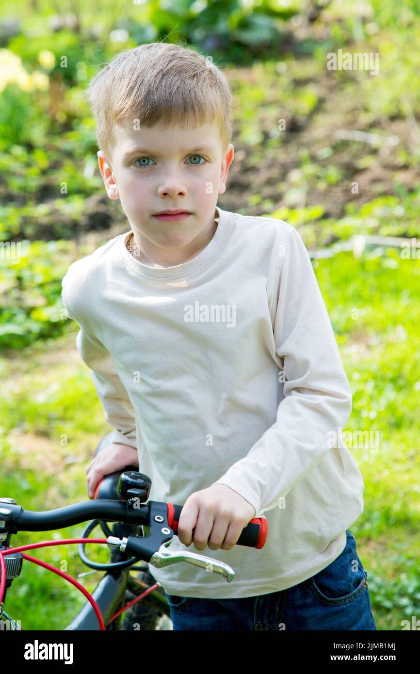 Il bambino è in piedi con una bicicletta in un giorno di primavera Foto Stock