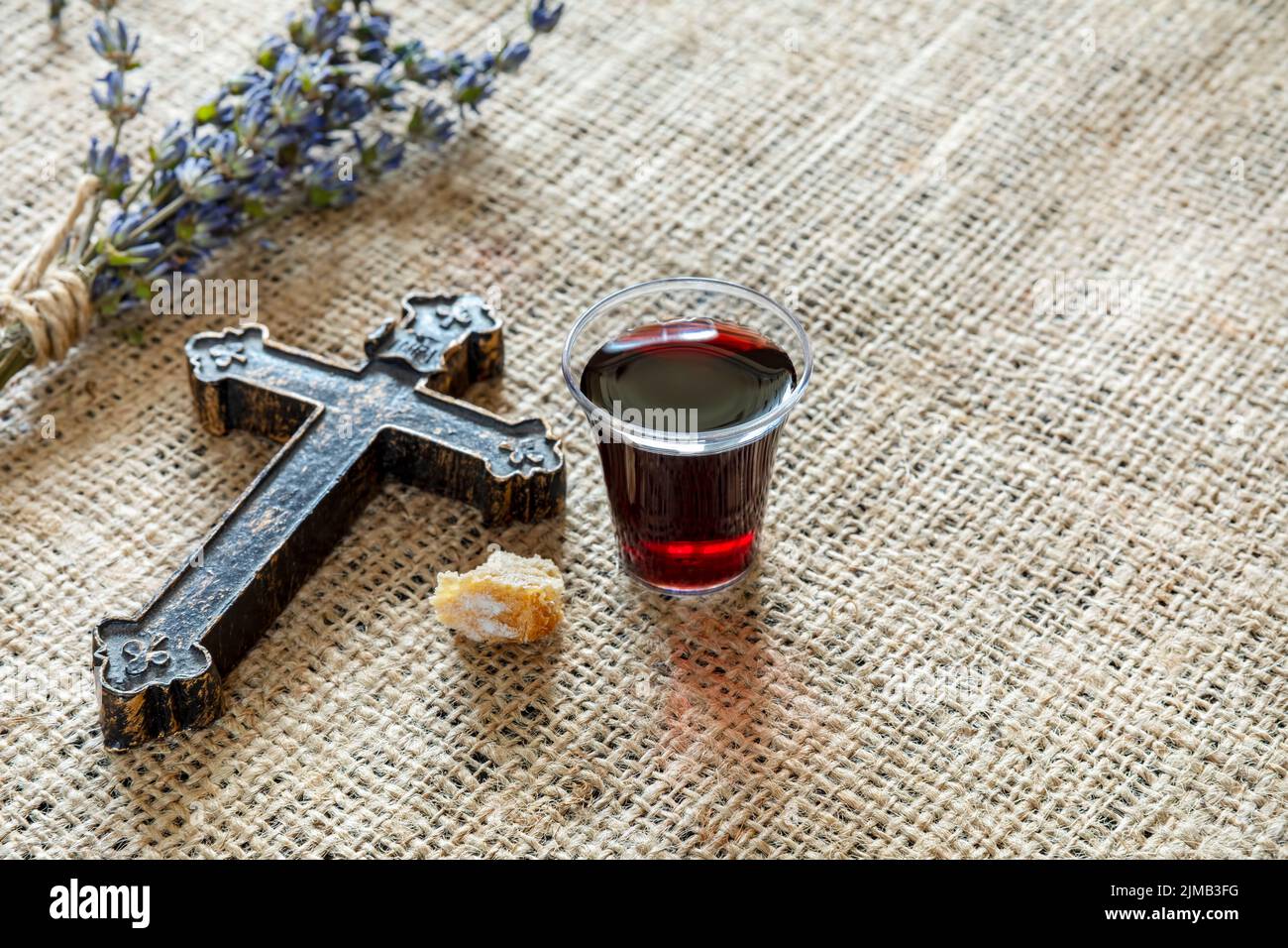 Comunione con un bicchiere di vino e pane vicino a croce e lavanda Foto Stock