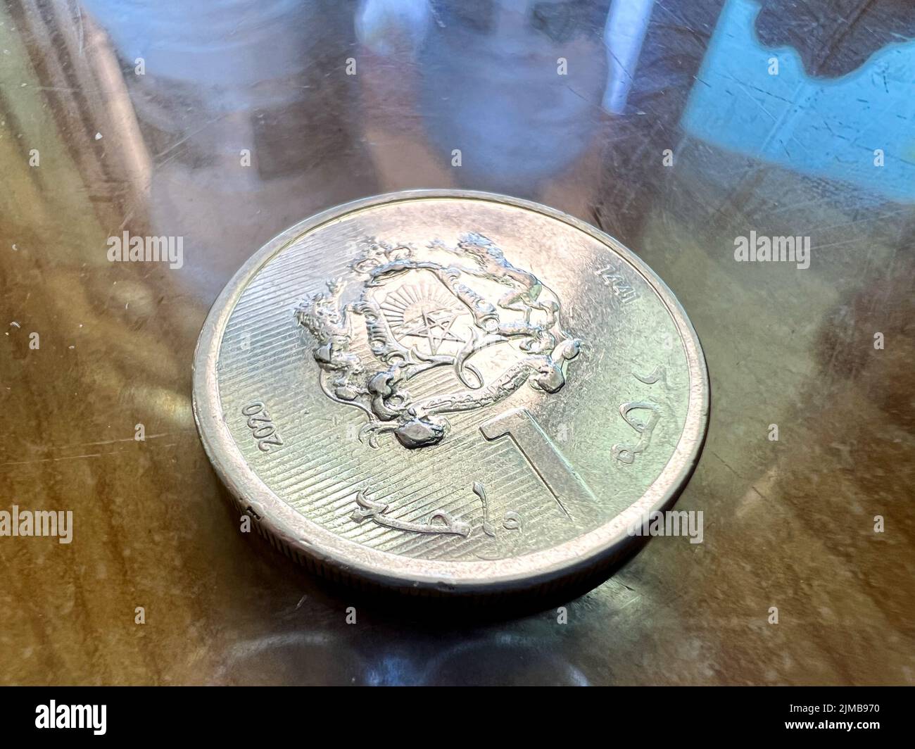 Primo piano di una moneta marocchina di Dirham su un tavolo marrone Foto Stock