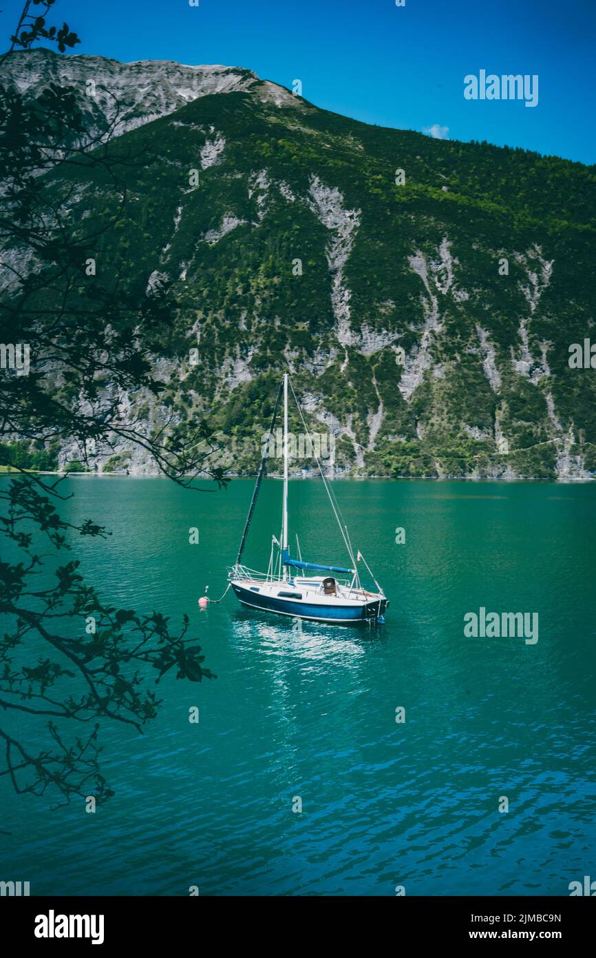 Uno yacht che naviga su un lago tranquillo in Austria contro una montagna Foto Stock