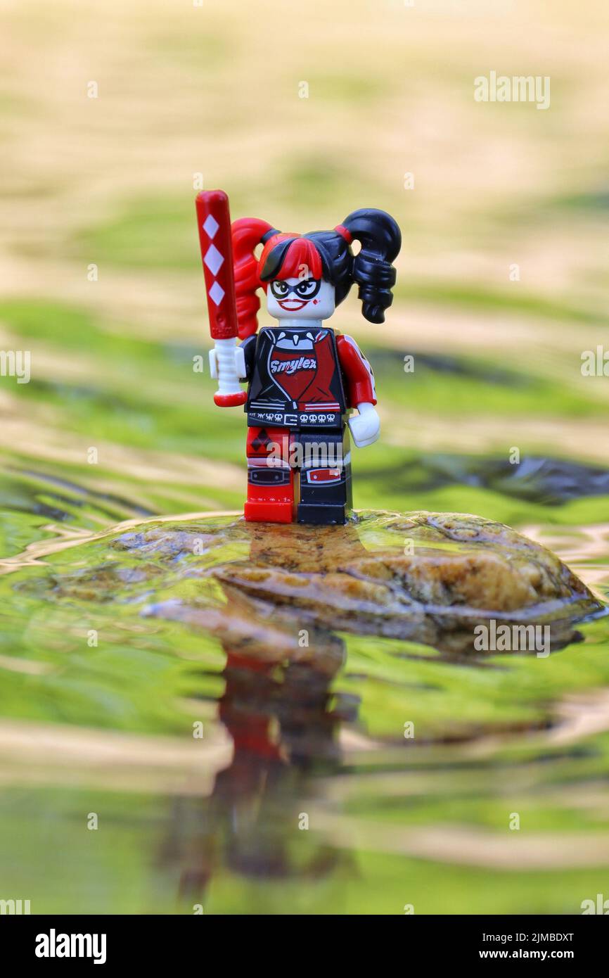 Personaggio femminile giocattolo, sorridente, in piedi e con una mazza da baseball vicino all'acqua. Foto Stock