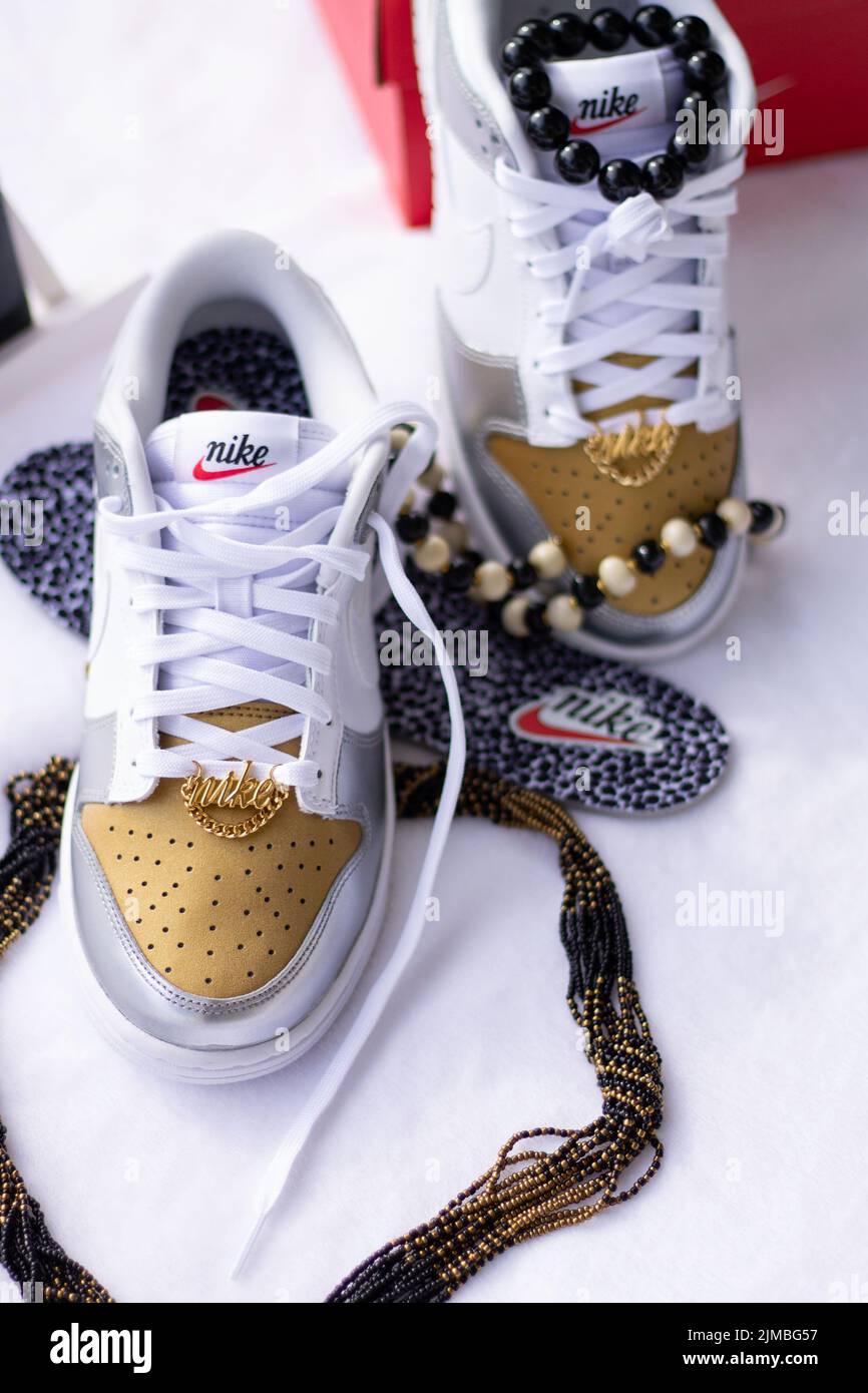 Una foto verticale di una sneaker bianca dal design dorato Foto Stock