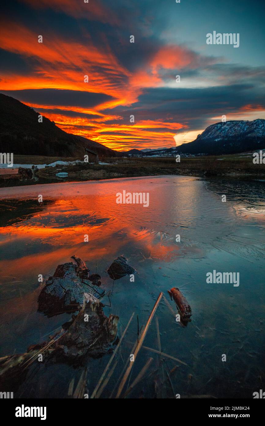 Tramonto rosso in un lago ghiacciato in inverno Foto Stock