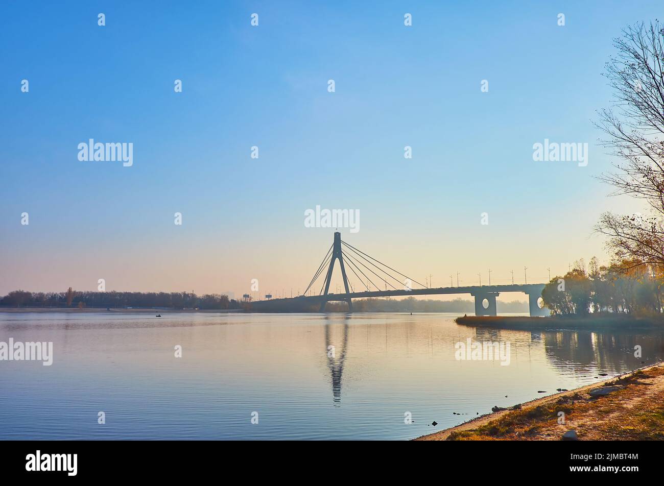 La mattina presto sul fiume Dnieper con una vista sul cielo luminoso dell'alba, il ponte di Pivnichnyi (nord) e le piante nei colori autunnali, Kiev, Ucraina Foto Stock