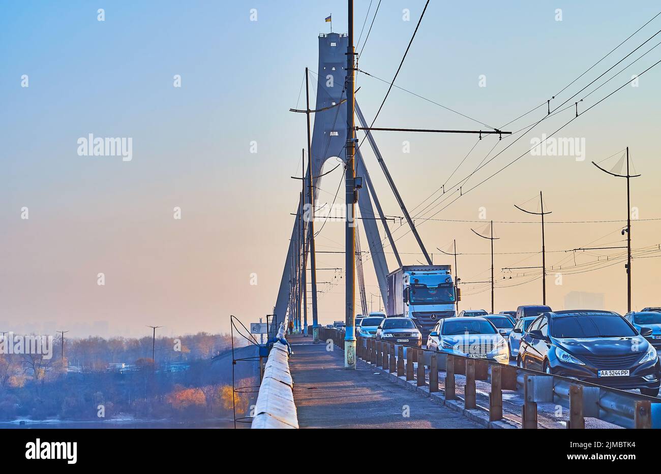 L'intenso traffico mattutino sul Ponte di Pivnichnyi (Nord) con una vista del cielo azzurro dell'alba e del fiume Dnieper, Kiev, Ucraina Foto Stock
