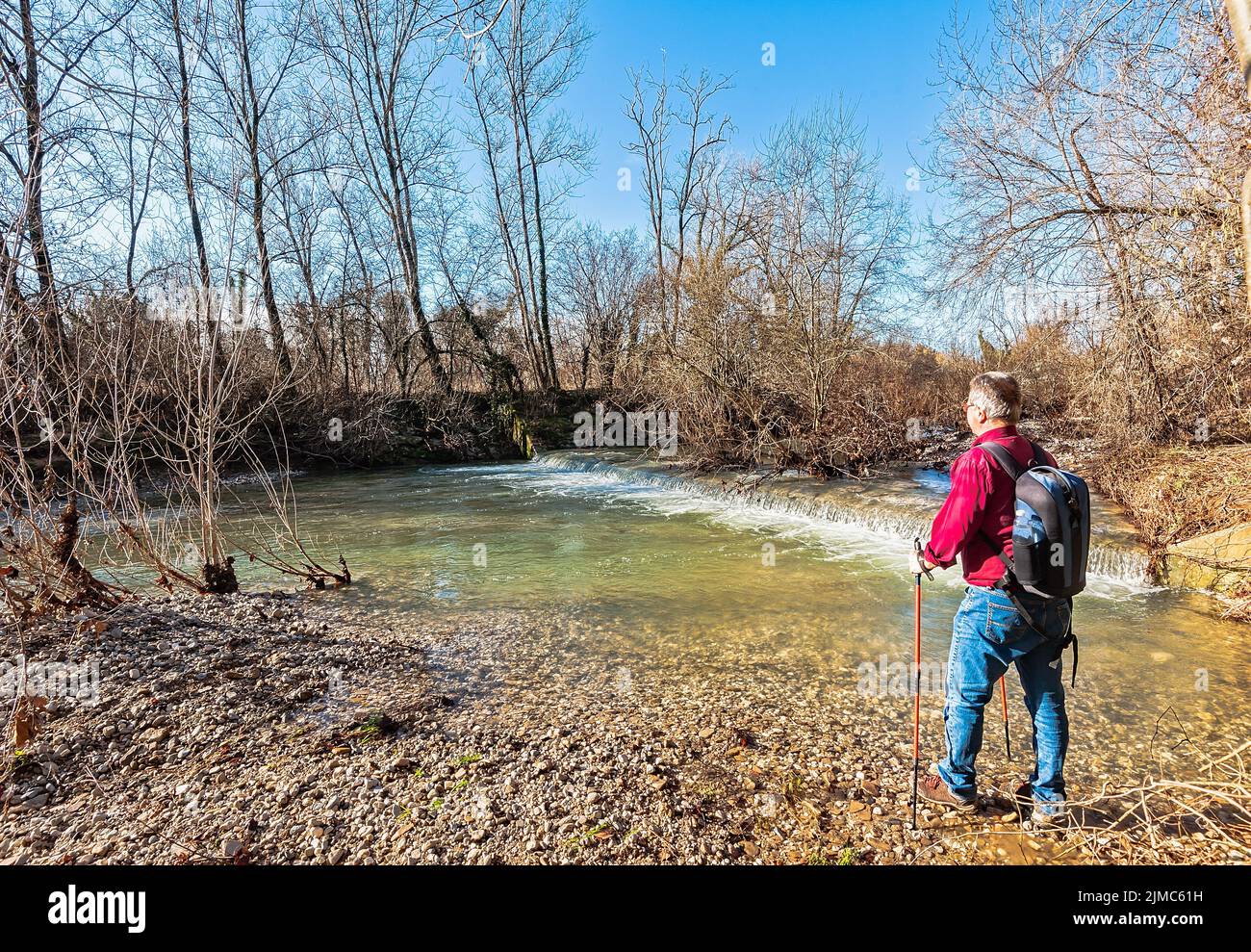 Escursionista di circa 60 anni, sulla riva del torrente. Foto Stock