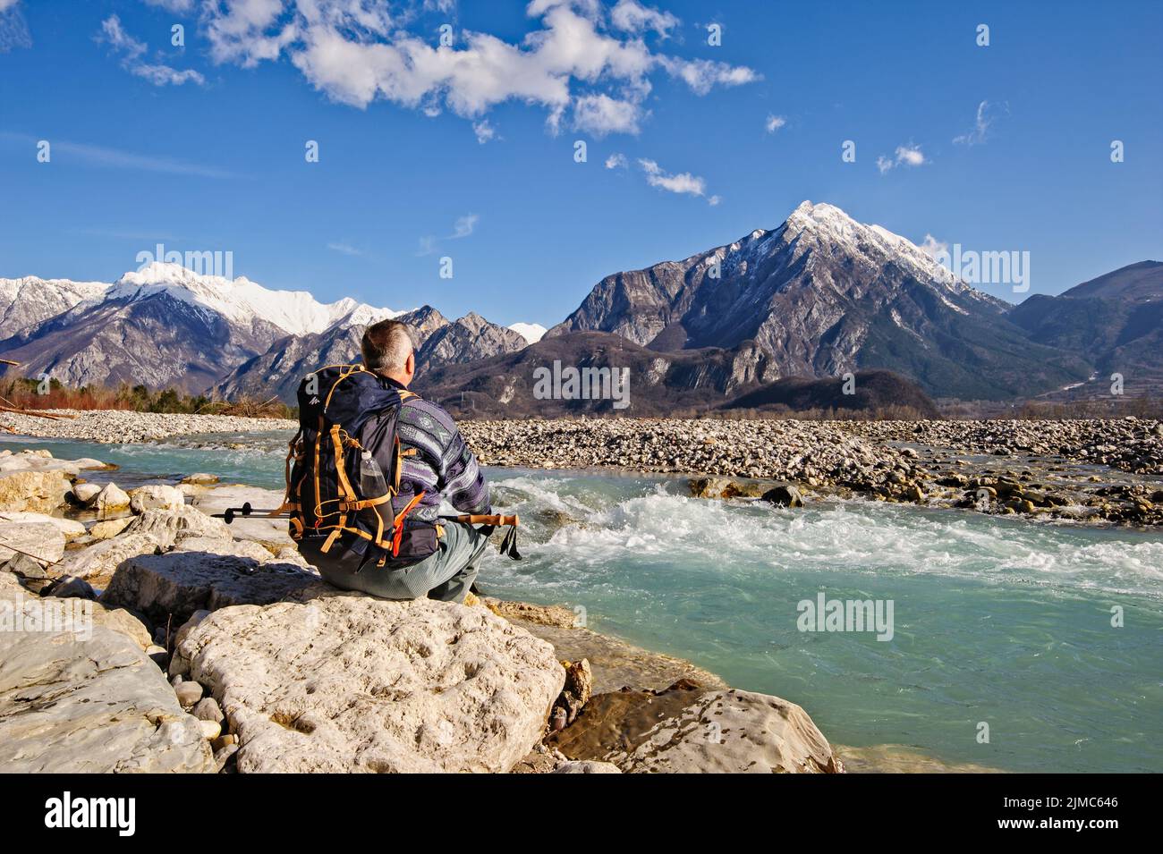 Escursionista seduto sulla riva del fiume, guardando le montagne paesaggio. Foto Stock