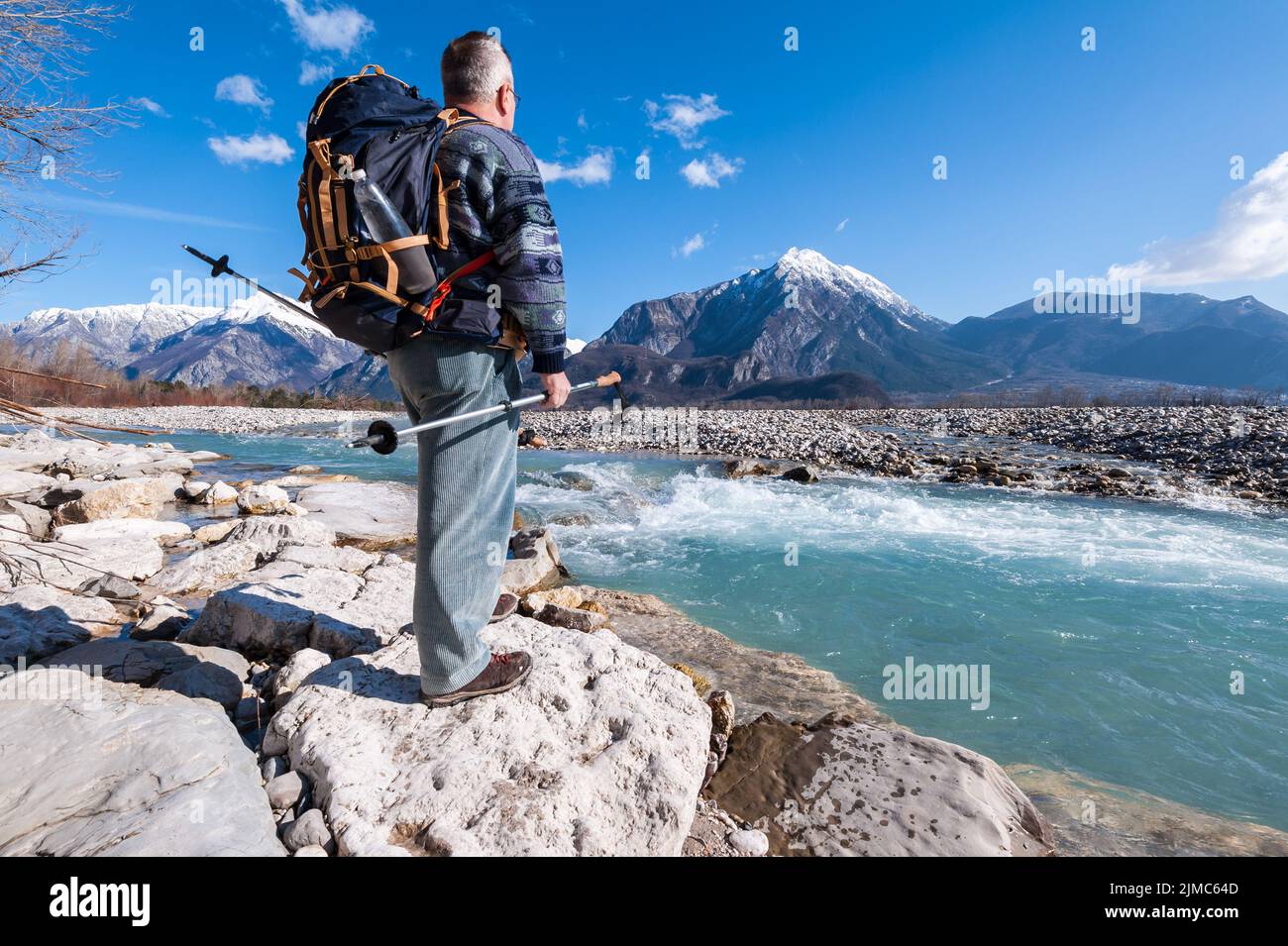 Escursionista in piedi sulla riva del fiume, guardando le montagne paesaggio. Foto Stock