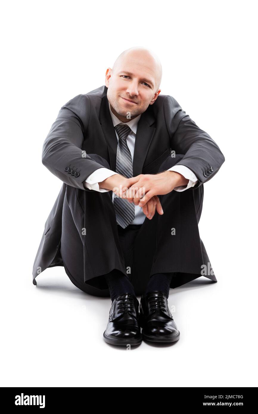 Bell'uomo d'affari sorridente e felice in vestito nero seduto al piano terra Foto Stock