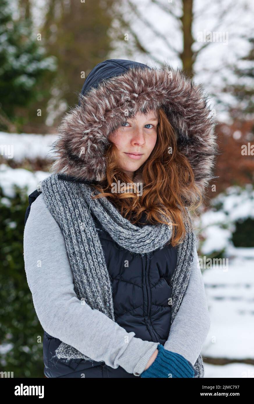 Ragazza giovane allegra in abiti invernali e cappuccio in pelliccia Foto Stock
