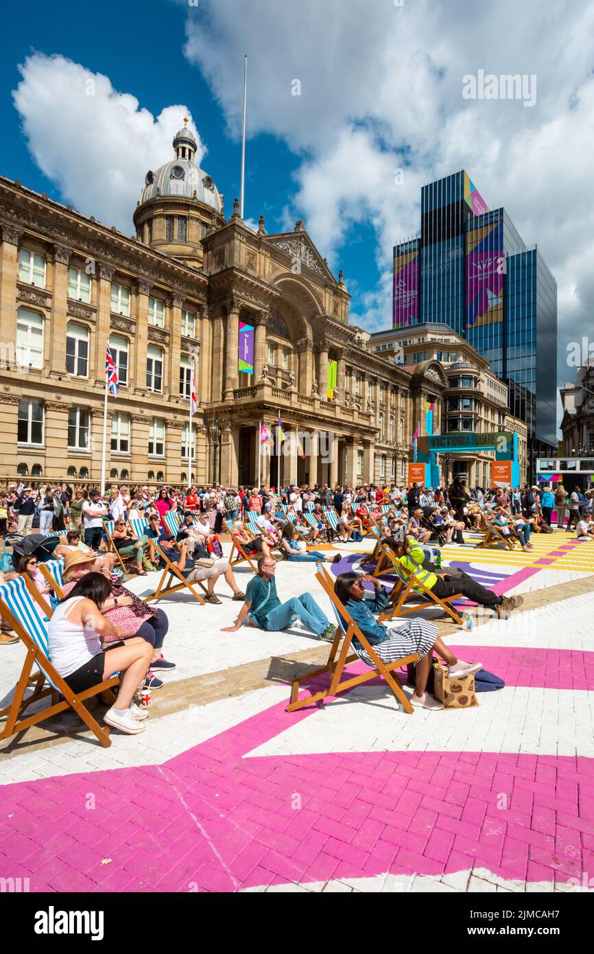 Una folla di spettatori che si godono il sole estivo in Victoria Square Birmingham guardando un grande schermo Commonwealth Games 2022 Foto Stock