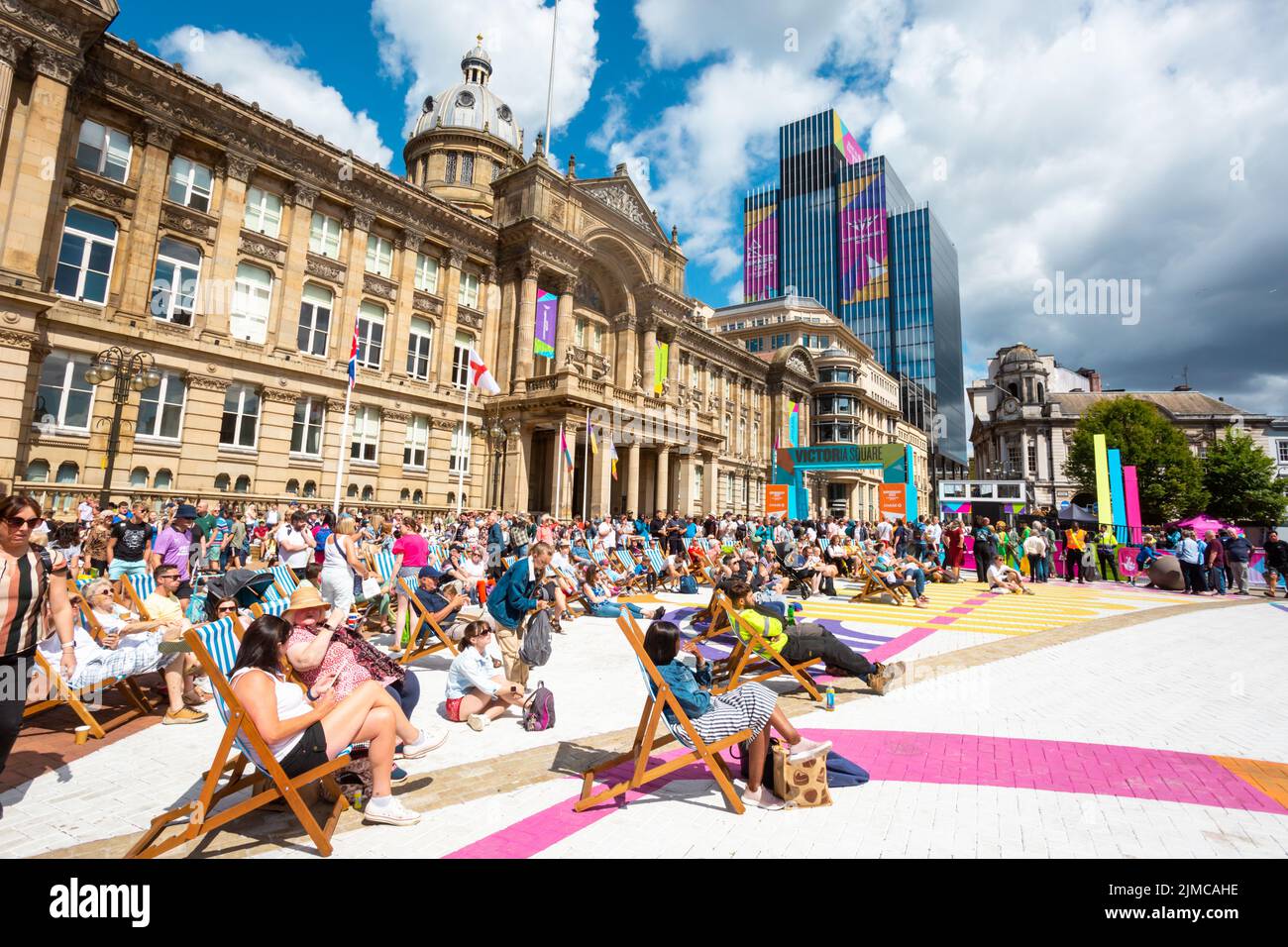 Una folla di spettatori che si godono il sole estivo in Victoria Square Birmingham guardando un grande schermo Commonwealth Games 2022 Foto Stock