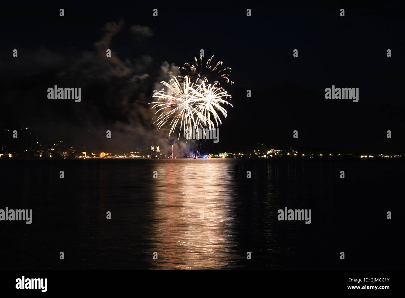 Splendidi fuochi d'artificio dorati che si illuminano nel cielo notturno e si riflettono sull'acqua di Tegernsee, Baviera, Germania Foto Stock