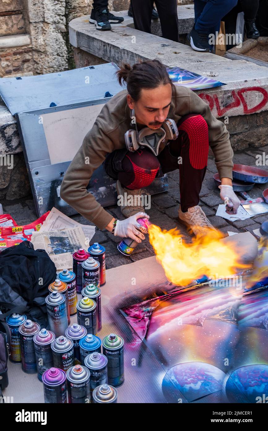 Un artista di strada dimostra la creazione di opere d'arte utilizzando bombolette spray e fuoco nel centro di Atene. Foto Stock