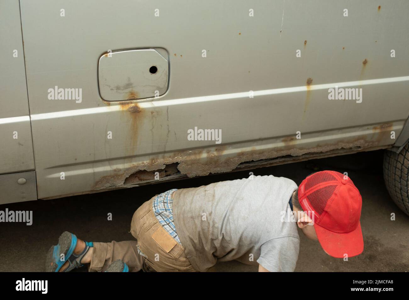 I bambini salono sotto l'auto. Preschooler in strada. È una situazione pericolosa. Scolaro incustodito. Foto Stock