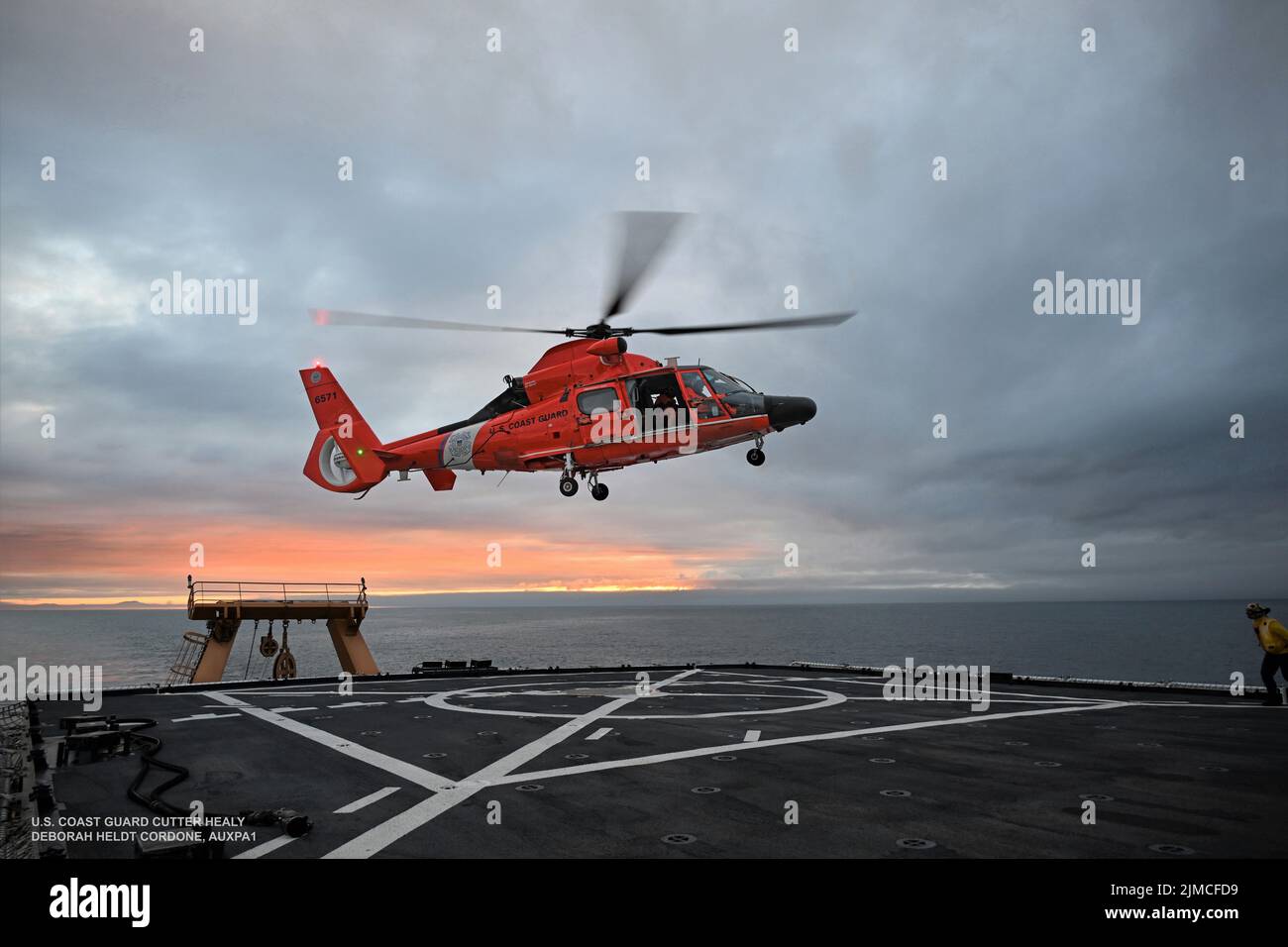 Un elicottero Kodiak MH-65 della Guardia Costiera statunitense atterra sul ponte di volo di Cutter Healy nel Circolo polare Artico il 21 luglio 2022. La formazione viene condotta regolarmente per mantenere le qualifiche dell'equipaggio a bordo di entrambi i beni e mantenere la competenza in una varietà di evoluzioni. Foto ausiliaria della Guardia Costiera degli Stati Uniti di Deborah Heldt. Foto Stock