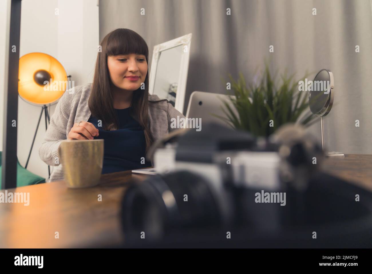 Bella giovane donna brunetta bere tè caldo al mattino e lavorare a distanza da casa utilizzando un computer portatile. Foto di alta qualità Foto Stock