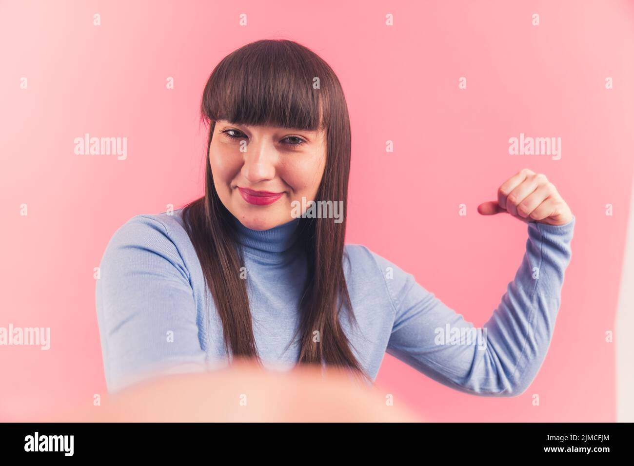 Sono forte. Fidata bella giovane donna bruna che mostra il suo braccio aka bicep alla fotocamera. Foto di alta qualità Foto Stock