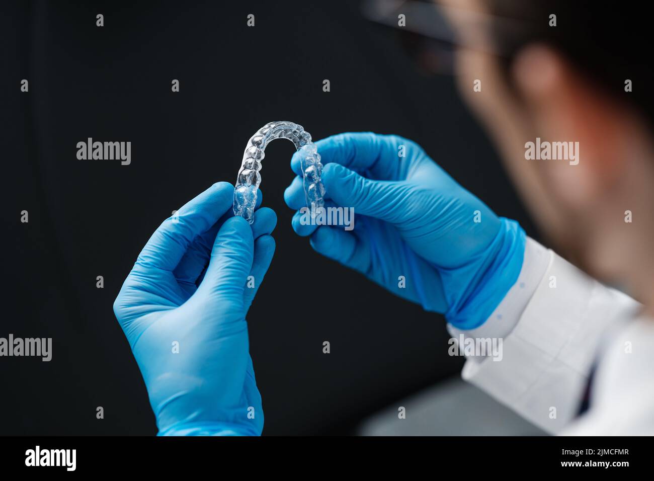 Ortodonzia invisibile cosmetici allineatori in mani di medico indossare guanti sterili isolati su uno sfondo nero, denti allineatori, bretelle in plastica. Mod Foto Stock