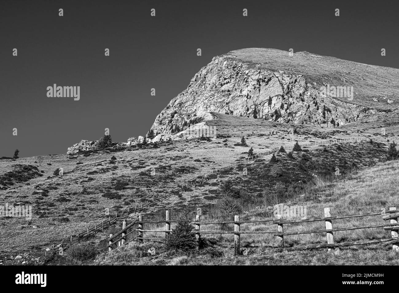 Cima rocciosa delle Ifinger Spitze, di fronte ad essa prati alpini con recinzioni in legno, foto in bianco e nero, area sciistica ed escursionistica di Merano Foto Stock