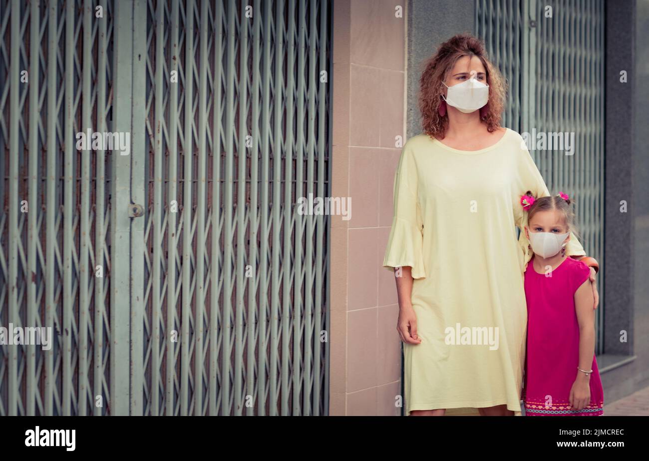 Donna e figlia che indossano una maschera facciale monouso. Protezione contro il coronavirus Foto Stock