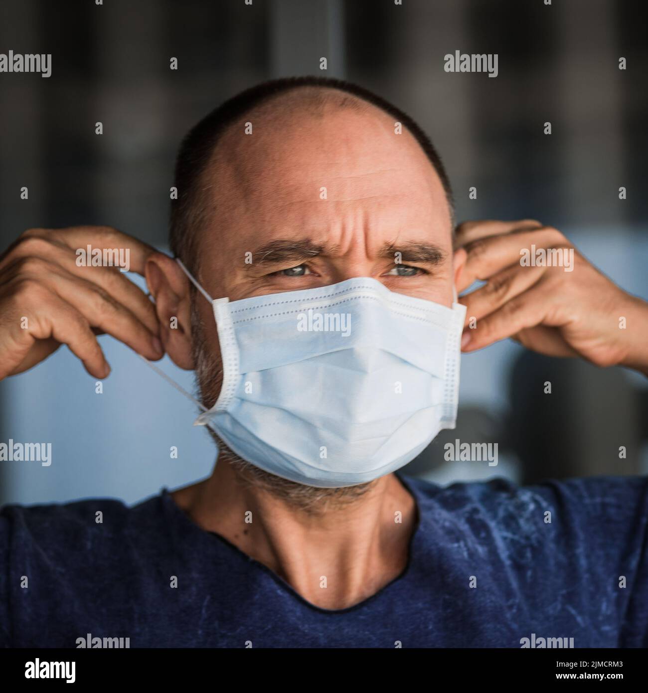 Uomo che indossa una maschera facciale monouso. Protezione da virus Foto Stock