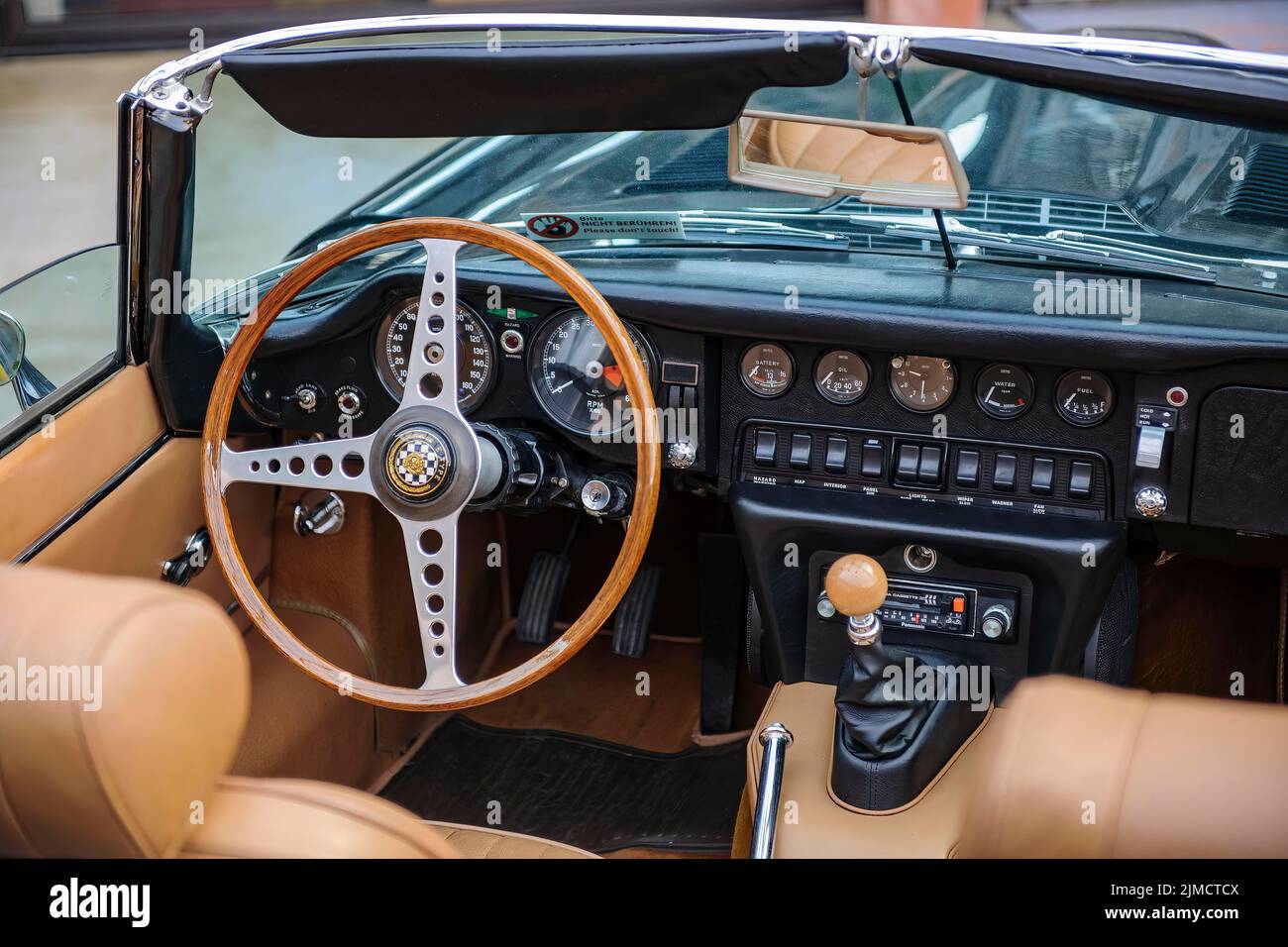 Vista all'interno della guida a sinistra in inglese storico classico auto sportiva classico roadster Jaguar e-Type con volante e cruscotto Foto Stock