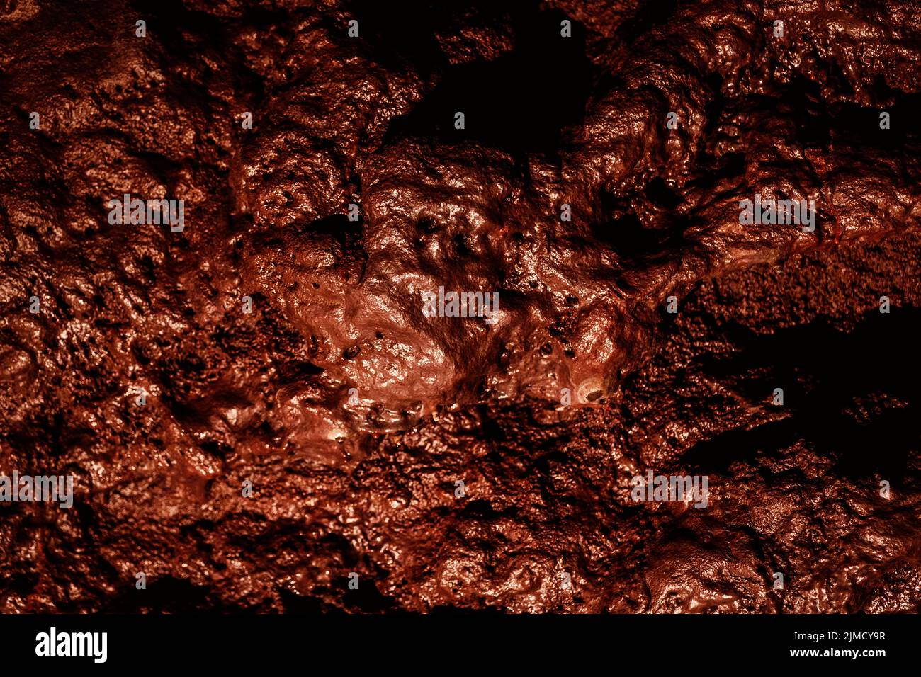 Parete ruvida marrone di grotta di lava con superficie irregolare come sfondo astratto Foto Stock