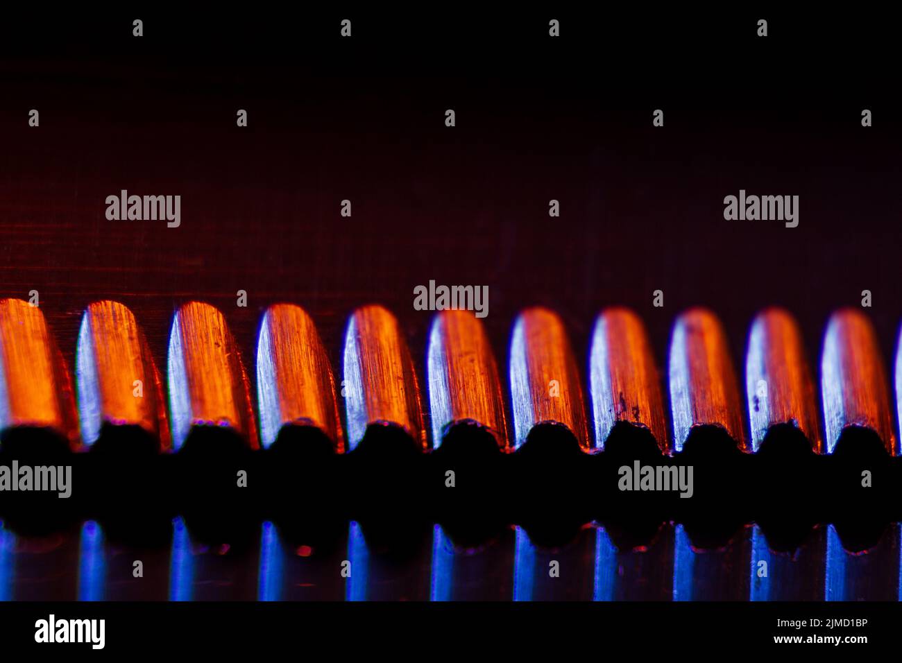 Bordo di un coltello seghettato illuminato e il loro macro-shot riflesso adatto come sfondo. Foto Stock
