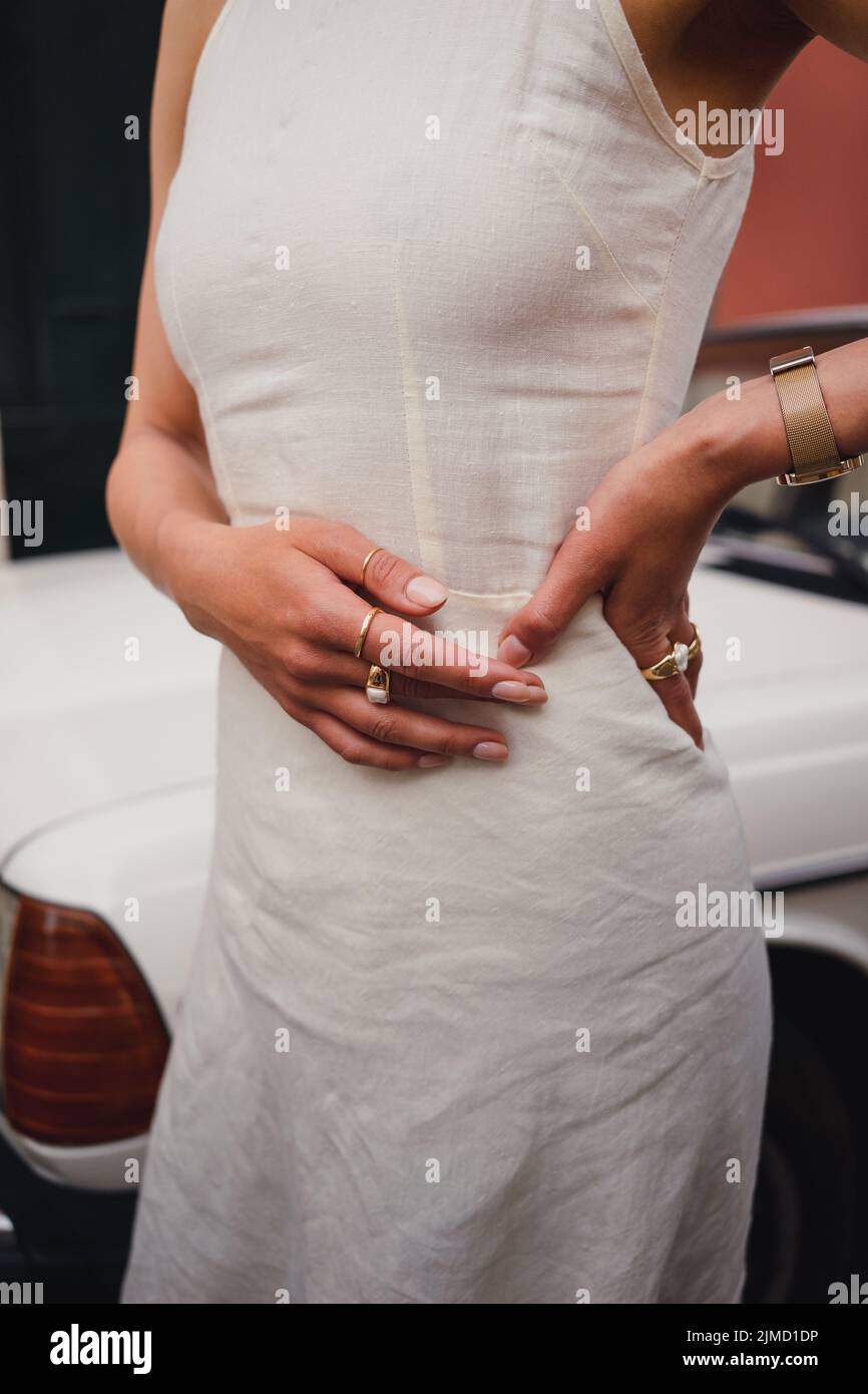 Crop anonymous femminile in elegante abito bianco in piedi con mano in vita  con accessori vicino auto in strada della città il giorno d'estate Foto  stock - Alamy