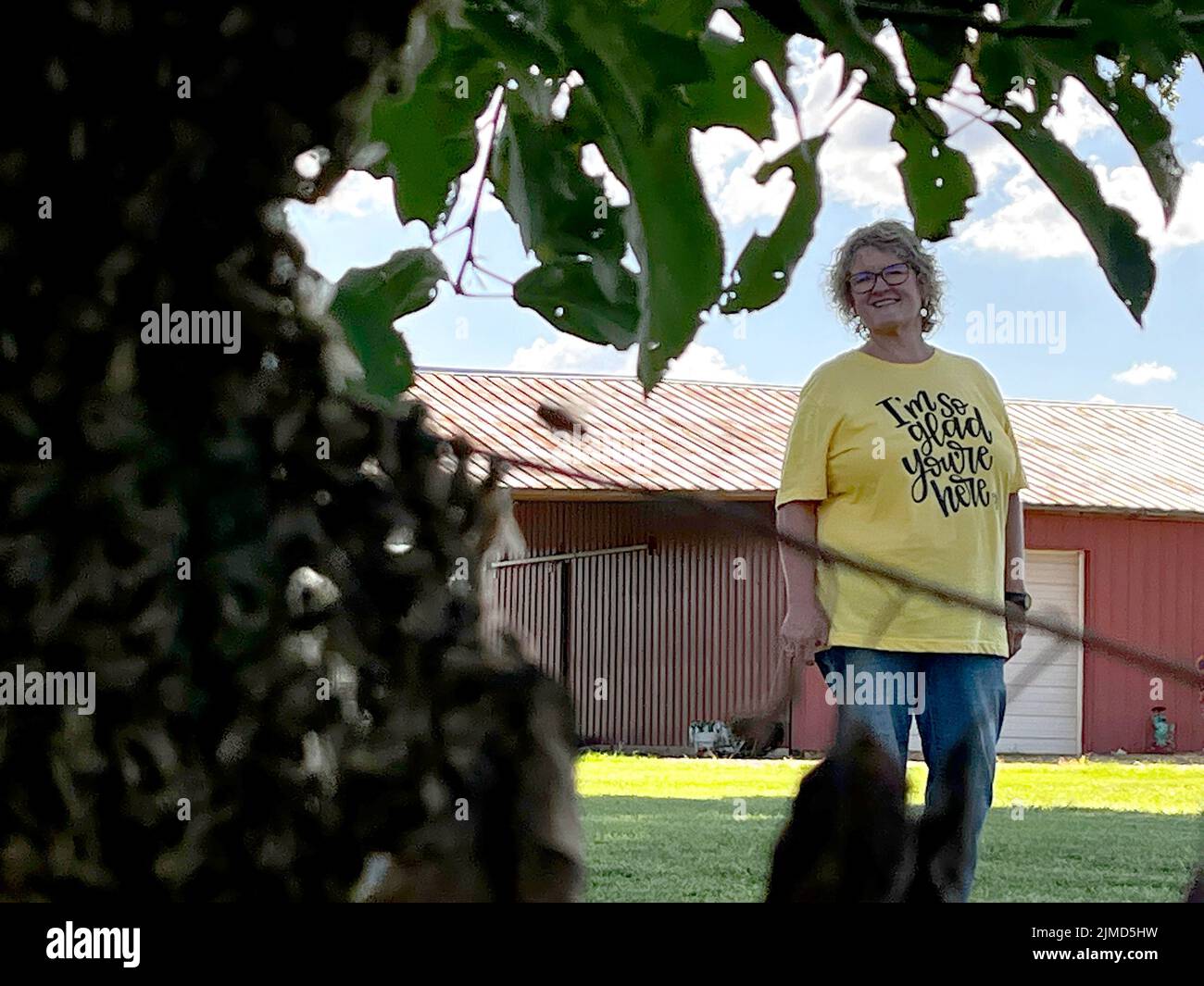 Ethelsville, Alabama USA 5th agosto 2022: Venerdì sera Pam Wright, a fuoco, si erge nel suo cortile vicino ad uno dei suoi alberi di mele dove uno sciame di api raggruppò su un ramo basso sospeso a sinistra. Aveva contattato gli apicoltori per prendere lo sciame. Secondo fonti miste le api melliere sciame a fine primavera o inizio estate, ma può anche verificarsi a fine luglio. Ethelsville si trova nella contea di Pickens, Alabama. Credit: Kelly Tippett/Alamy Live News Foto Stock
