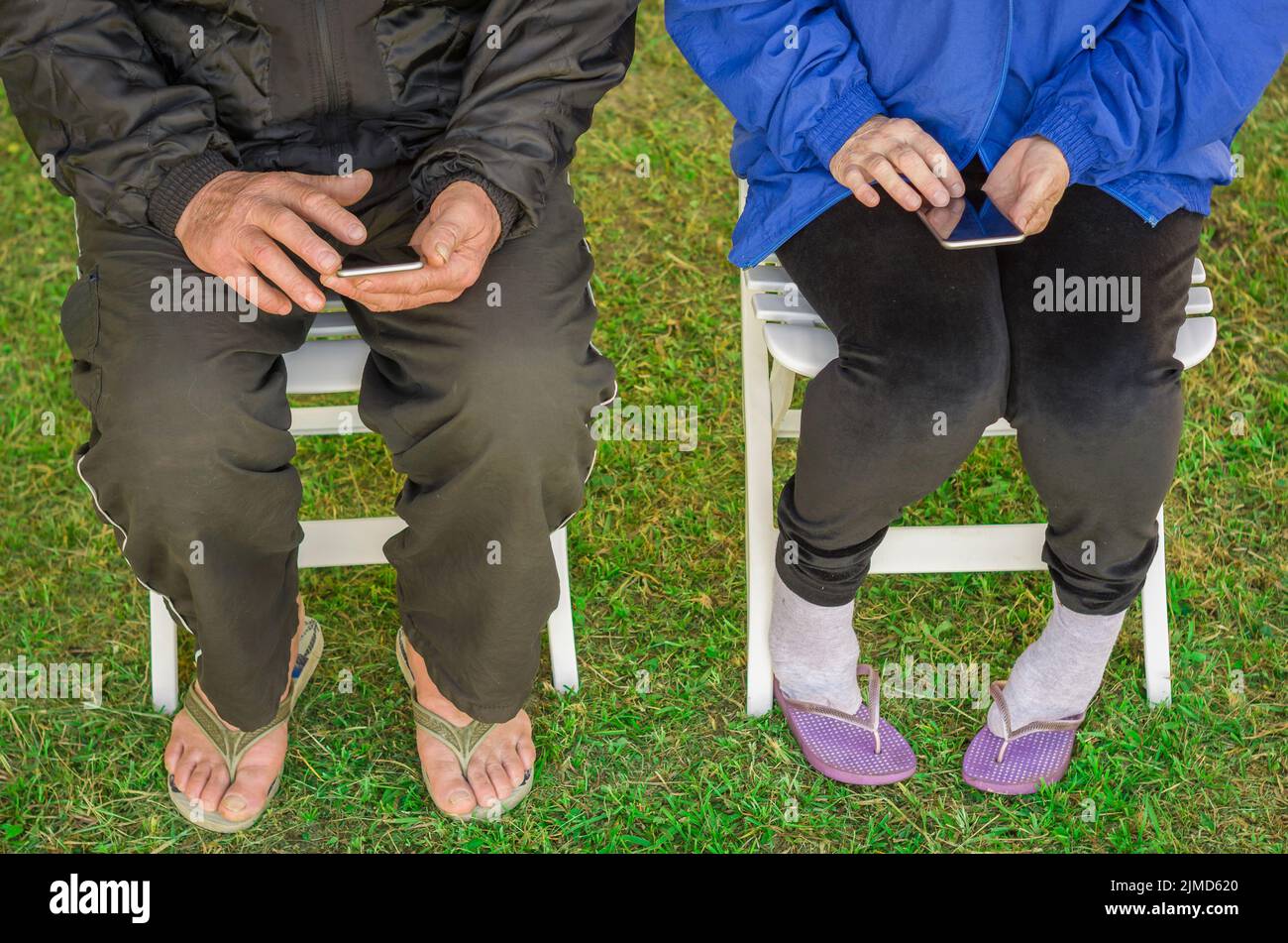 In prossimità della coppia di anziani seduti, utilizza lo smartphone, telefoni cellulari, la tecnologia. Foto Stock