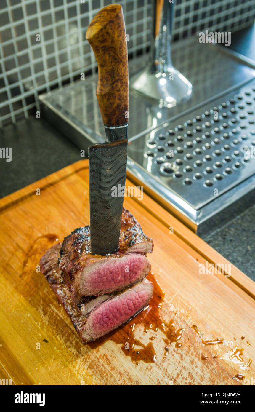 Bellissima foto di brisket di manzo (punta di Brisket fine). Taglio di carne con coltello in acciaio Damasco forgiato Arkan Foto Stock