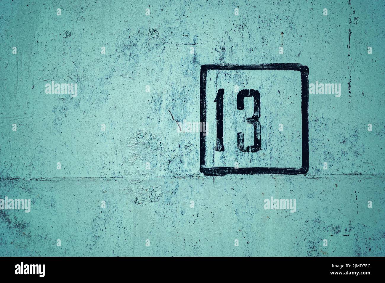 Il numero 13 è stenciled in cornice nera su parete di cemento verde, copia spazio Foto Stock