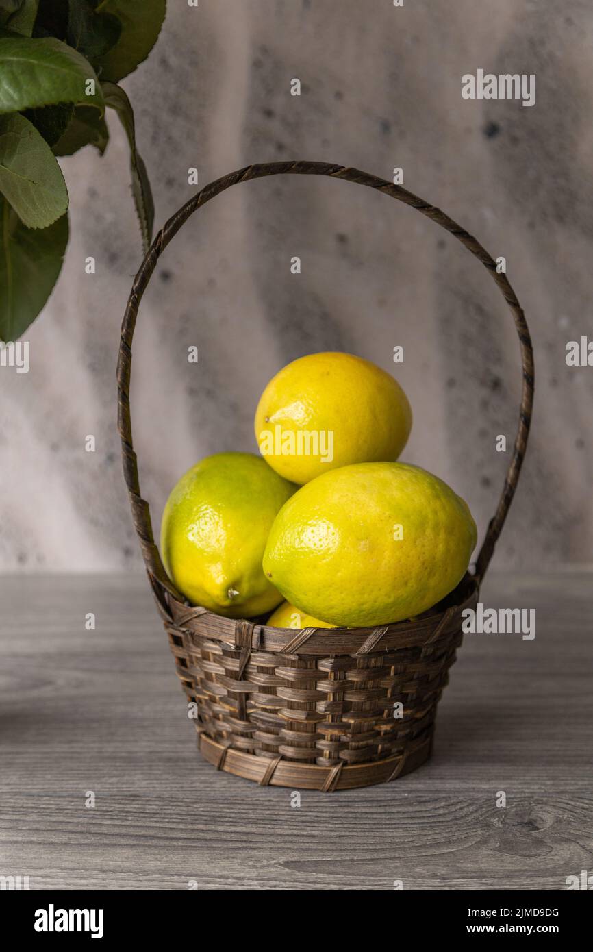 bellissimo pezzo centrale con un cesto di vimini e qualche frutto della passione fresca, frutta come decorazione in studio, dettagli texture Foto Stock