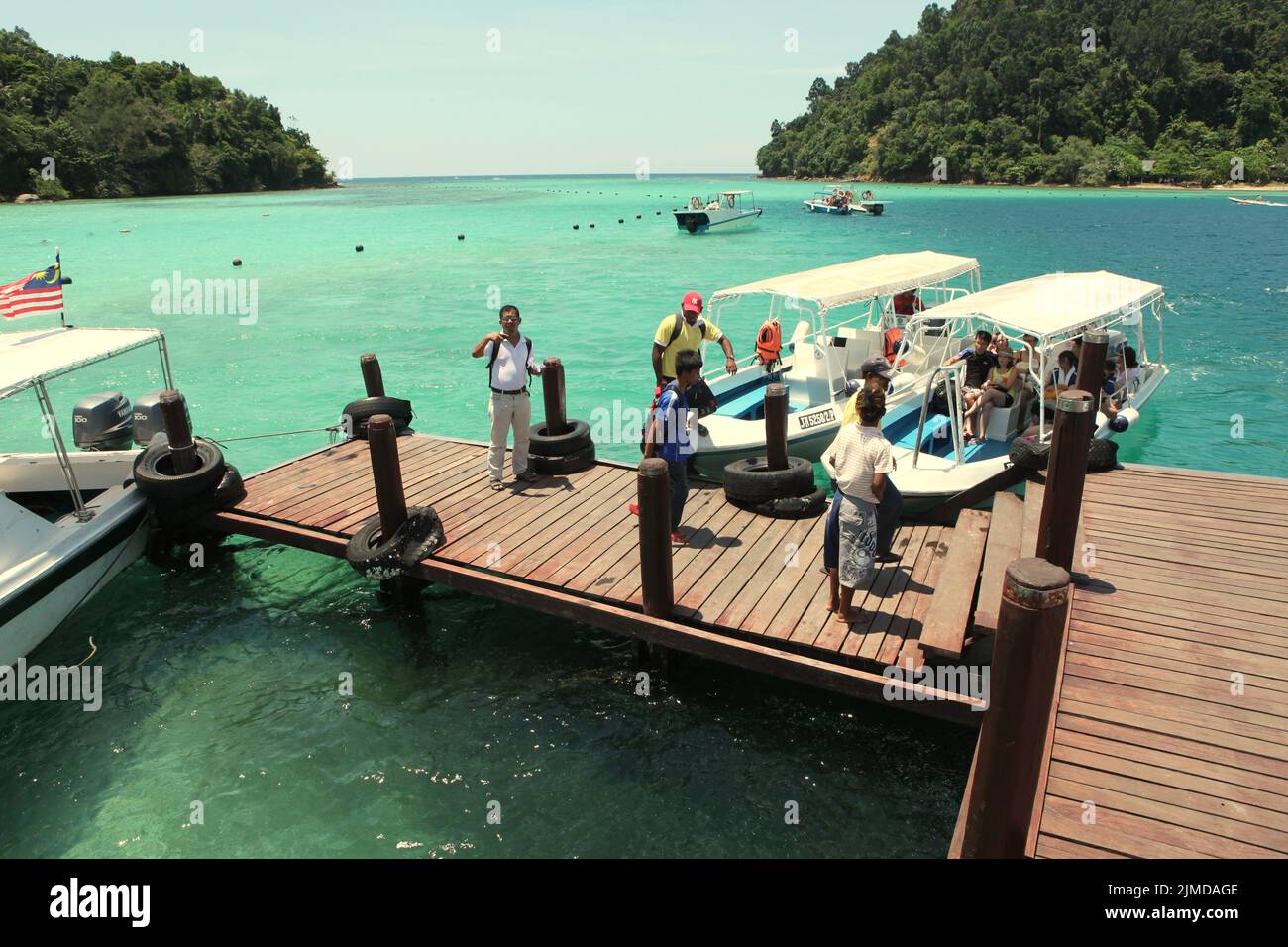 I visitatori escono dalle barche mentre arrivano a un molo su Pulau Sapi (Isola Sapi), una parte del Parco Tunku Abdul Rahman a Sabah, Malesia. Foto Stock