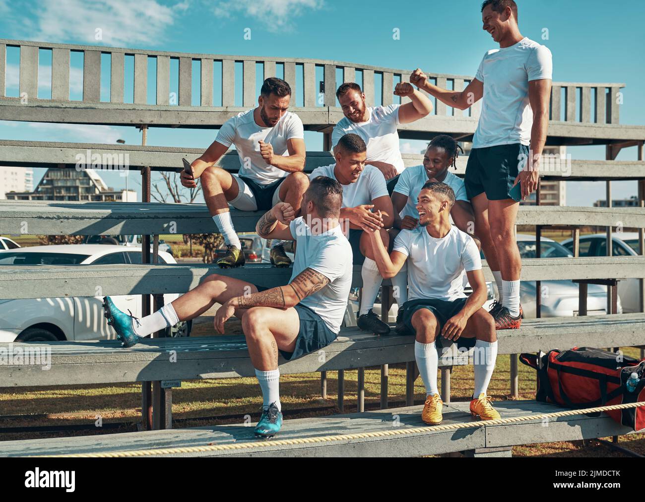 Heres alcuni suggerimenti per portare il nostro gioco a un livello superiore. Un giocatore di rugby che mostra qualcosa ai suoi compagni di squadra sul suo cellulare. Foto Stock