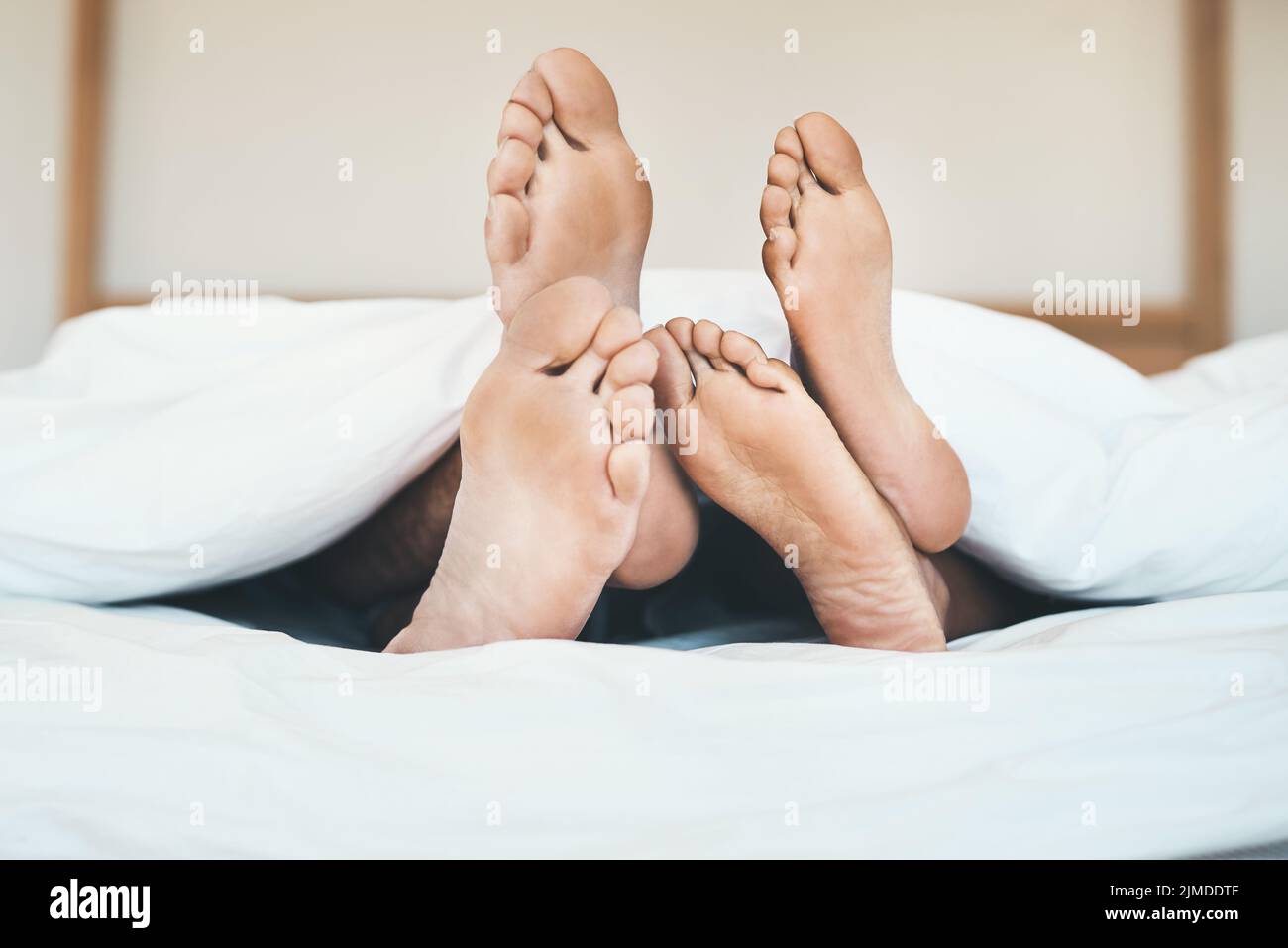 I piedi di una coppia innamorata che si trova a letto, rilassandosi e legandosi insieme a casa. Primo piano di un ragazzo a piedi nudi e ragazza che dormono, riposano o. Foto Stock