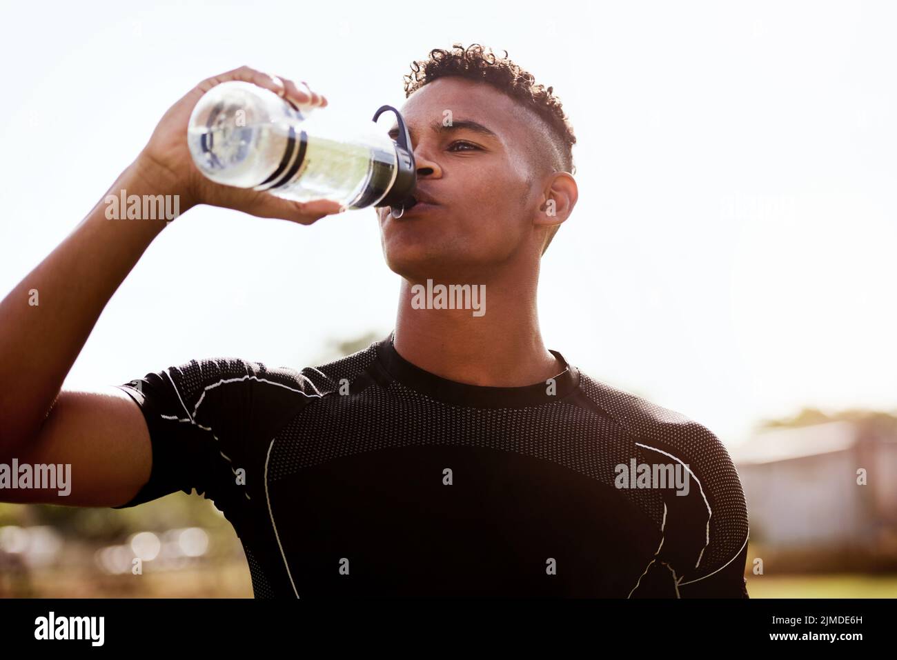 Niente risolve una sete come il rugby. Un giovane che beve acqua dopo aver giocato una partita di rugby. Foto Stock
