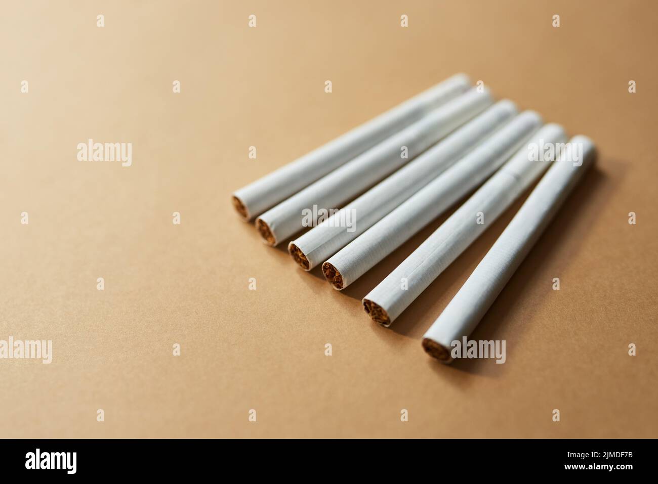 Alcune abitudini sono più difficili da rompere. Studio girato di una fila di sigarette su uno sfondo marrone. Foto Stock
