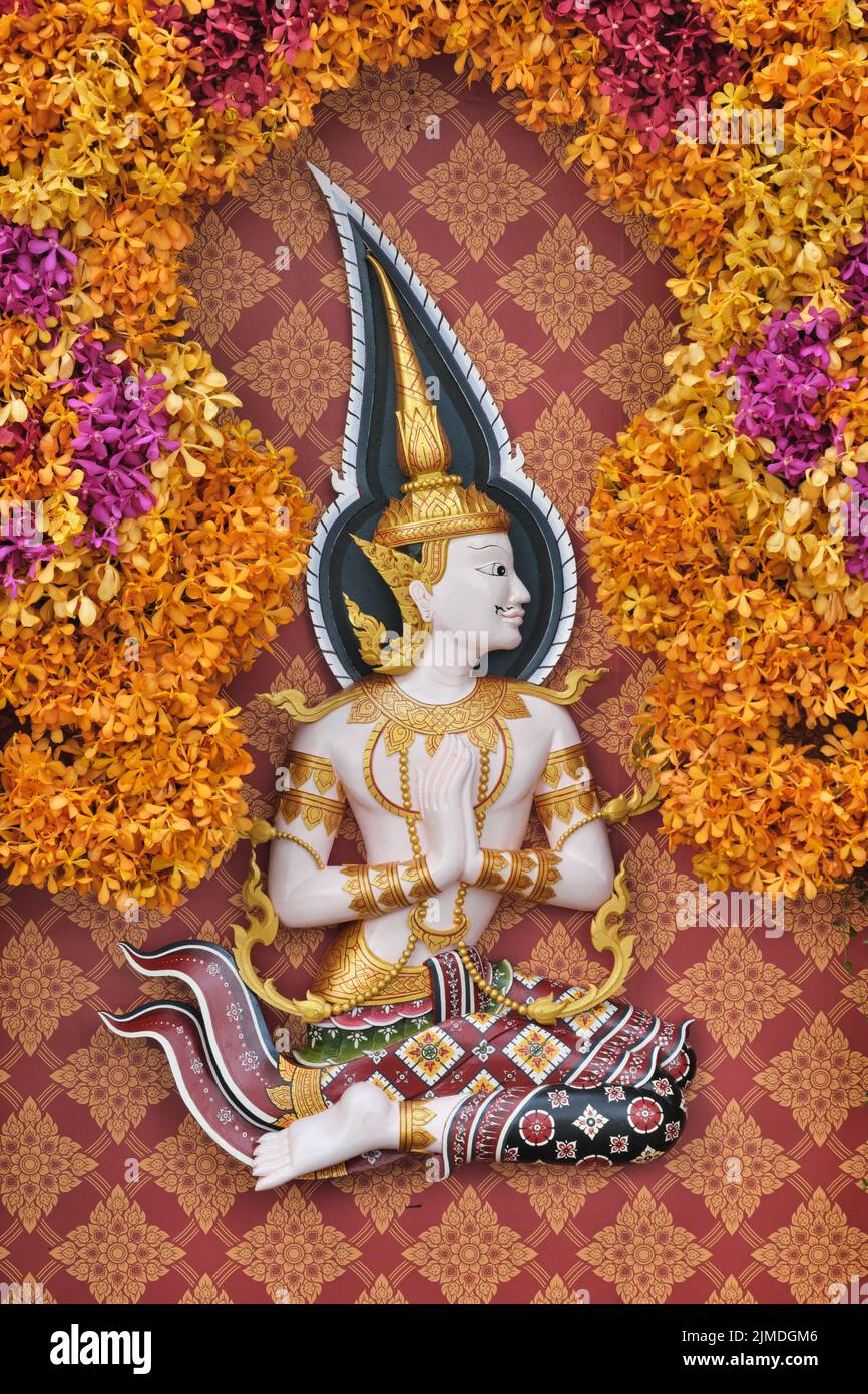 Una composizione floreale con un Apsara, un essere mitologico. Esecuzione del tradizionale e rispettoso saluto tailandese chiamato Wai; Bangkok, Thailandia Foto Stock