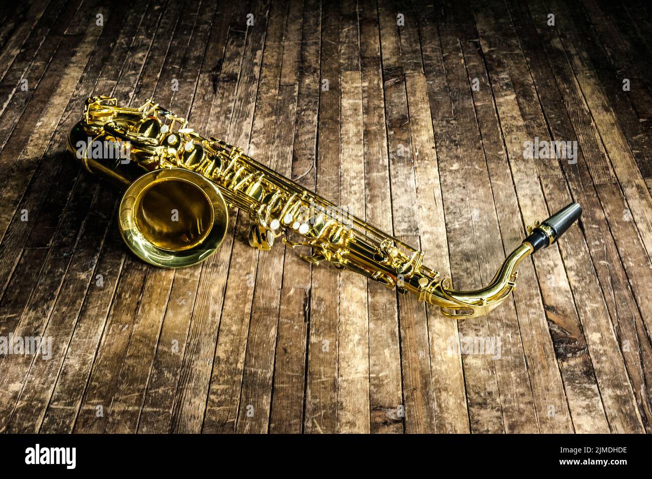 Il sassofono dello strumento musicale jazz giallo si trova su un palcoscenico di legno marrone Foto Stock